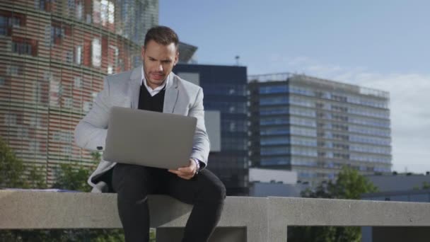 Businessman using laptop for video call outdoors. Freelancer working on laptop - Metraje, vídeo