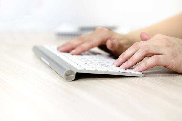 Kobiece ręce na białej klawiaturze bezprzewodowej, zbliżenie i widok z boku.  - Zdjęcie, obraz