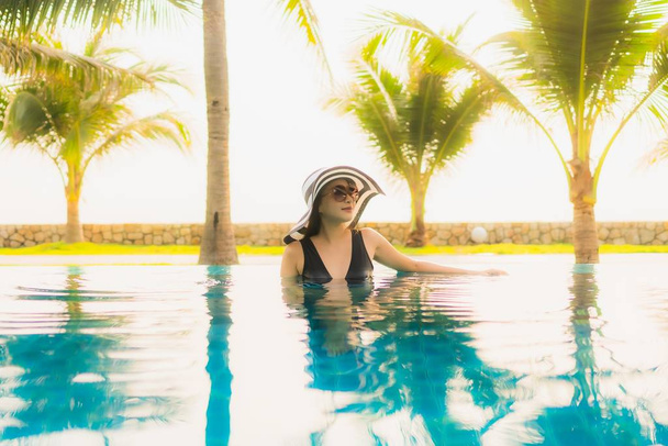 Portrait beautiful young asian woman relax around outdoor swimming pool in hotel resort with palm tree at sunset or sunrise for leisure vacation - Photo, Image