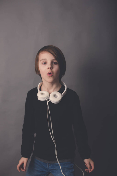 Sweet child, boy in black sweater, listening music, isolated background - Foto, Imagen