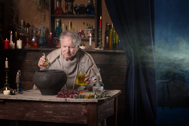 elderly alchemist monk brews  magic potion - Foto, afbeelding