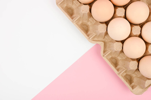 Egy tálca tojás, fehér és rózsaszín háttérrel. ökotálca herékkel. Minimalista trend, felülnézet. Tojásos tálca. Húsvét fogalma - Fotó, kép