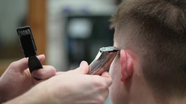 Young mans haircut in Barbershop. Close-up of master clipping hair with clipper - Video, Çekim