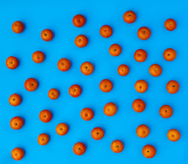 Many orange mandarins on a blue background. Tropical fruits. Top view - 写真・画像