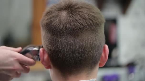Joven hombre corte de pelo en la barbería. Primer plano del maestro cortando a un hombre con el pelo rubio con la cortadora
 - Imágenes, Vídeo