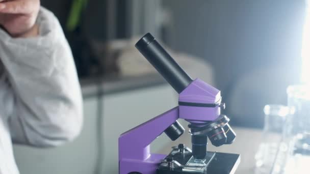 scientist in laboratory in goggles looking into microscope.  Scientific discoveries in Microbiology or pharmacology. Laboratory tools: microscope, test tubes. Research in biology. Medical discovery - Metraje, vídeo