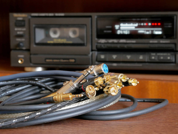 Kabeltoebehoren voor muzikanten en luisteraars van kwaliteitsmuziek. Audio connectoren type jack, rca, stereo, xlr. Een cassettespeler is op de achtergrond. - Foto, afbeelding