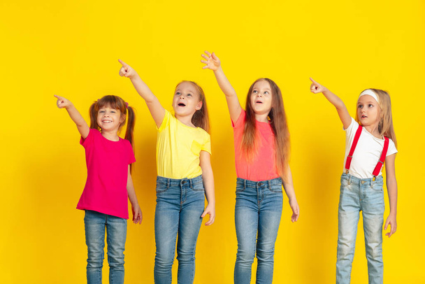 Happy children playing and having fun together on yellow studio background - Fotoğraf, Görsel