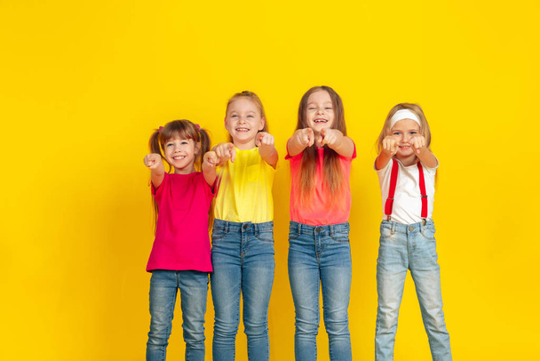 Enfants heureux jouant et s'amusant ensemble sur fond jaune studio
 - Photo, image