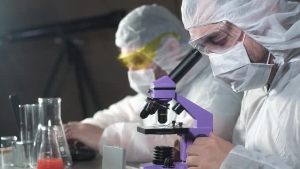 Laboratuvardaki iki bilim adamı araştırma yapıyor. Bir dizüstü bilgisayardaki mikroskop parmak izi verilerini inceler. Başarı ya da keşifle sevinin. Virüs ve aşı yüzünden. Tıbbi bir laboratuarda deney.. - Video, Çekim