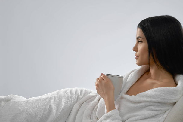 Brunette in bathrobe drinking morning coffee. - Фото, изображение