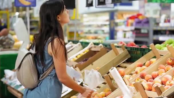 A young woman buys fruit in a supermarket. - Felvétel, videó