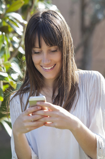 Happy girl texting on a smart phone outdoor - Foto, afbeelding