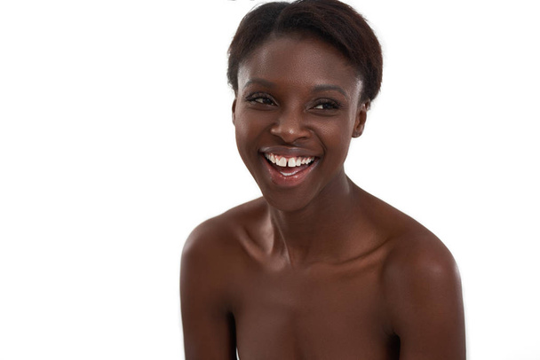Smiling beauty. Portrait of a young and cheerful african woman laughing and looking away while standing against white background - Photo, Image