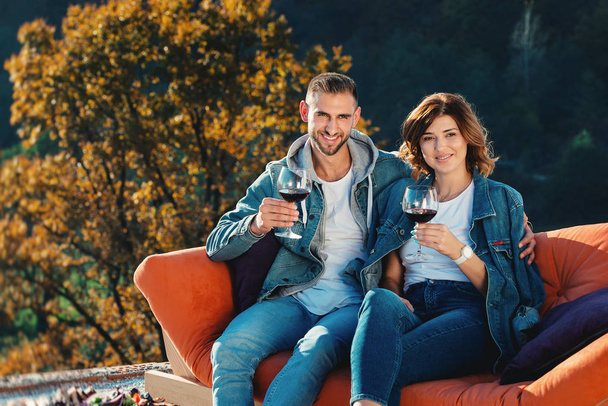 νεαρό ζευγάρι γιορτάζει την αγορά ενός νέου σπιτιού. Χαμογελαστοί σύζυγοι με ποτήρια κόκκινο κρασί στα χέρια - Φωτογραφία, εικόνα