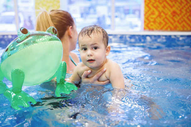 Γυναίκα εκπαιδευτής παιδιών και νήπιο κολύμπι και μελέτη σε μπλε πισίνα νερού - Φωτογραφία, εικόνα