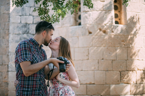 Milovníci fotit atrakce v blízkosti kamenné zdi chrámu. Pár novomanželů obdivuje starobylou církev. Líbánky na cestách - Fotografie, Obrázek