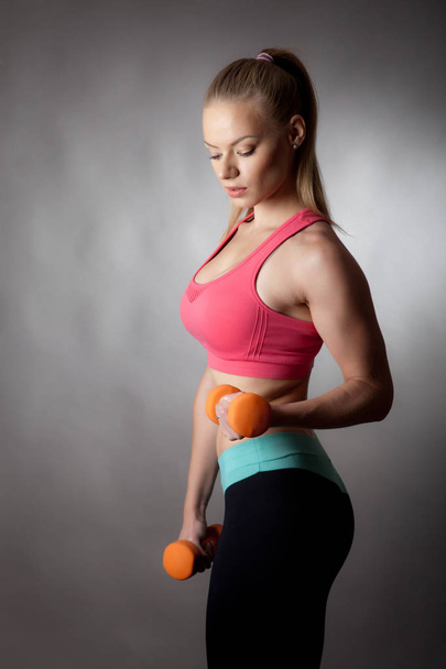 young athletic woman works out with dumbbells to improve her figure - Фото, зображення