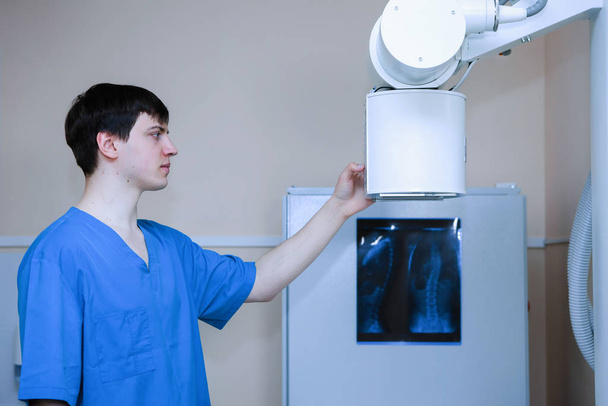 Αρσενικός ακτινολόγος ιατρός προετοιμάζει εξοπλισμό για ακτινογραφίες σε ιατρικό γραφείο. - Φωτογραφία, εικόνα