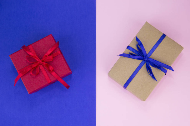 Gift with a blue and red ribbon on a double background. Kraft gift box with blue ribbon. Pink and blue background. - Fotó, kép