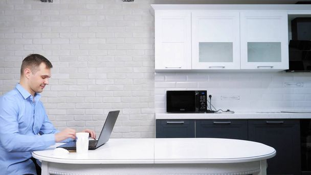 businessman using his laptop while sitting at the table in the kitchen - Foto, Imagem