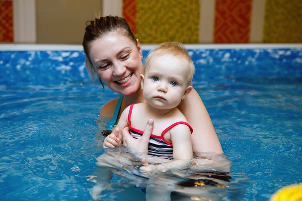 Mulher criança treinador e criança nadar e estudar na piscina de água azul
 - Foto, Imagem