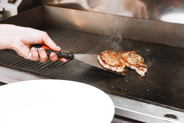 Cucini prepara un hamburger: frigge una polpettina di carne su un bruciatore
. - Foto, immagini
