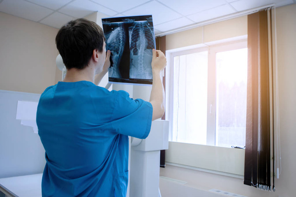 Αρσενικός ακτινολόγος γιατρός εξετάζει ακτινογραφίες σε ένα ιατρικό γραφείο. - Φωτογραφία, εικόνα
