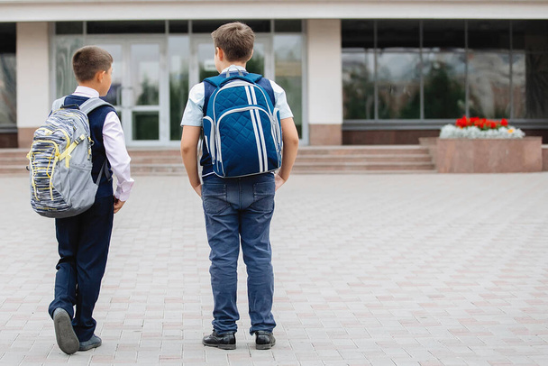 Zwei Teenager in Schuluniformen mit Rucksäcken gehen zur Schule. - Foto, Bild