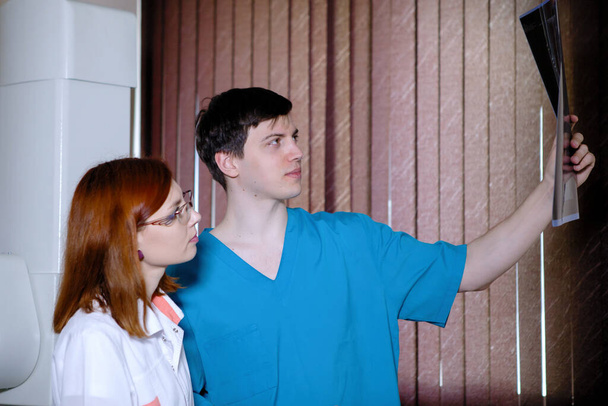Γυναίκες και άνδρες γιατροί ακτινολόγοι μελετούν ακτινογραφίες σε ένα ιατρικό γραφείο. - Φωτογραφία, εικόνα