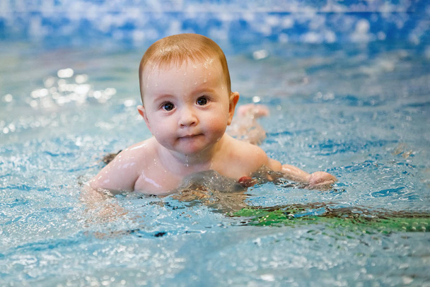 Söpö vauva uima-altaassa, jossa on sinistä vettä. Uimakoulutus, terveelliset elämäntavat
. - Valokuva, kuva