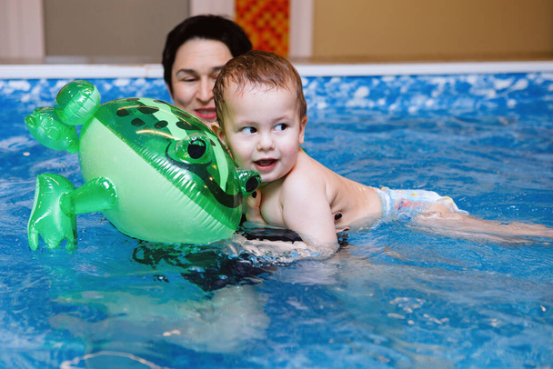 Mujer entrenador de niños y niños pequeños nadan y estudian en la piscina de agua azul
 - Foto, imagen