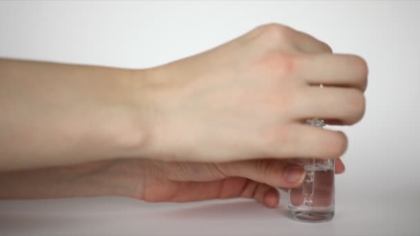 Hyaluronic acid drop falls from cosmetic pipette on hand, woman rubs funds hand on white background - Video, Çekim