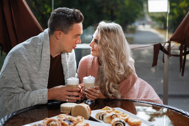 Dos amantes, un hombre y una mujer en una mesa en un café. Abrazo, caricia, beber café con leche. Feliz pareja tradicional, felicidad familiar
. - Foto, imagen