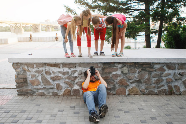 Aufnahmen von Kindern von einem Fotografen, Regisseur, Filmemacher, die auf dem Bürgersteig liegen. Harte Arbeit, Kunst erfordert Opfer. - Foto, Bild