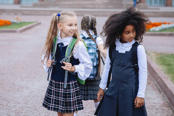 Two schoolgirls in uniform in skirts and golfs. Look back at school after school. - 写真・画像