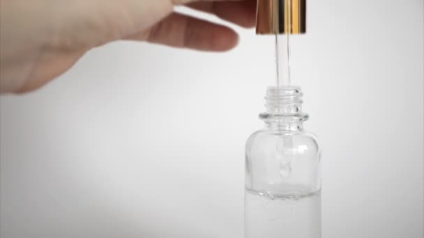 Hyaluronzuur druppel valt uit cosmetische pipet op witte achtergrond, Dropper glazen fles Mock-Up - Video