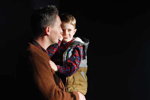 Ο πατέρας κρατάει τον γιο του στην αγκαλιά του. Γονική αγάπη, ευτυχισμένη παιδική ηλικία, φροντίδα των παιδιών. - Φωτογραφία, εικόνα
