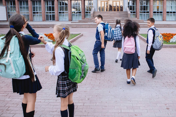 Uczniowie w mundurach spotykają się przed szkołą, by chodzić na zajęcia.. - Zdjęcie, obraz