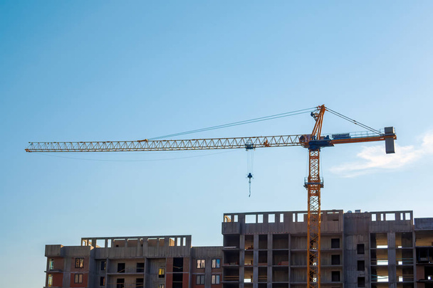 Construction of high panel building. Construction crane on blue sky daytime: Ufa, Russia - May 30, 2019 - Foto, afbeelding