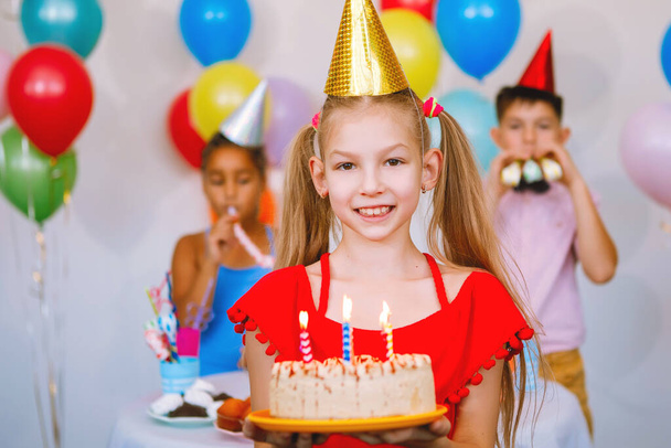 Child holding a cake with a candle on a birthday celebration. Holiday concept. - Photo, Image