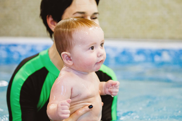 Woman child trainer and toddler swim and study in blue water pool - Photo, Image