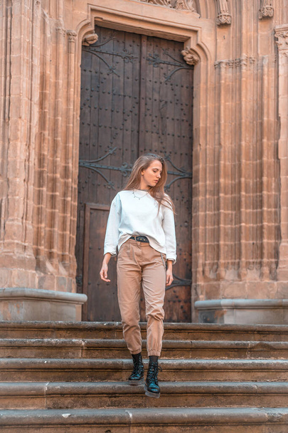 Beautiful young woman posing near entrance to cathedral - Foto, Bild