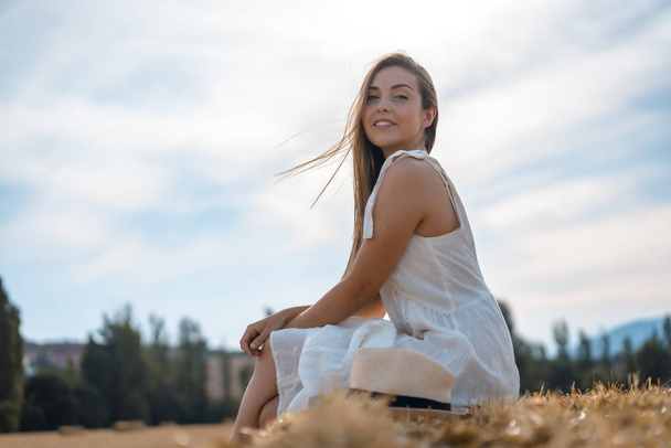 portrait of beautiful young woman wearing white dress in rural field - Fotografie, Obrázek