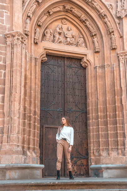 Beautiful young woman posing near entrance to cathedral - Foto, imagen
