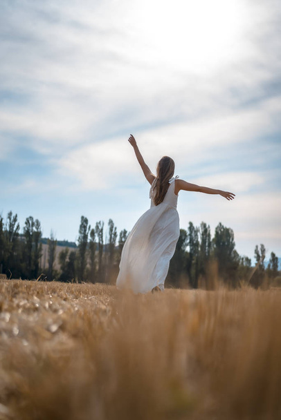 portrait of beautiful young woman wearing white dress in rural field - Photo, image