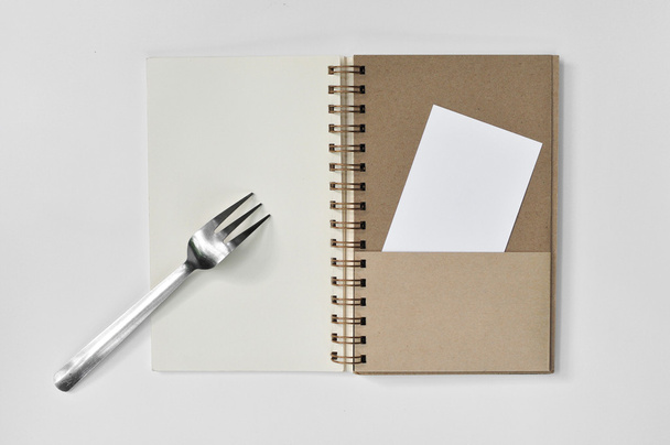 Blocco note bianco con forchetta e un pezzo di carta su sfondo bianco
 - Foto, immagini