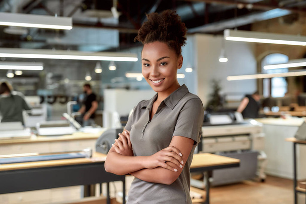 Aloita hienoja asioita. Hymyilevä afrikkalainen amerikkalainen toimistotyöntekijä poseeraa kädet ristissä
 - Valokuva, kuva