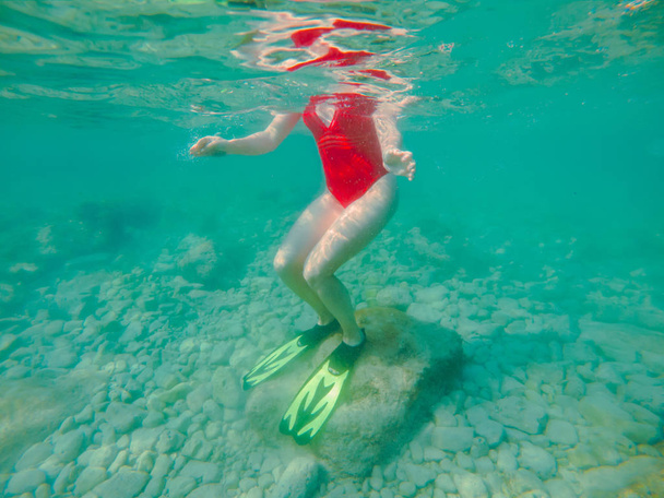 Kırmızı mayo giyen, şnorkel maskeli ve yüzgeçli bir kadın yaz tatili için su altında. - Fotoğraf, Görsel
