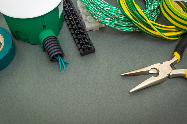 Peças sobresselentes verdes, ferramentas e fios para substituição ou reparação de equipamento eléctrico sobre fundo cinzento
 - Foto, Imagem